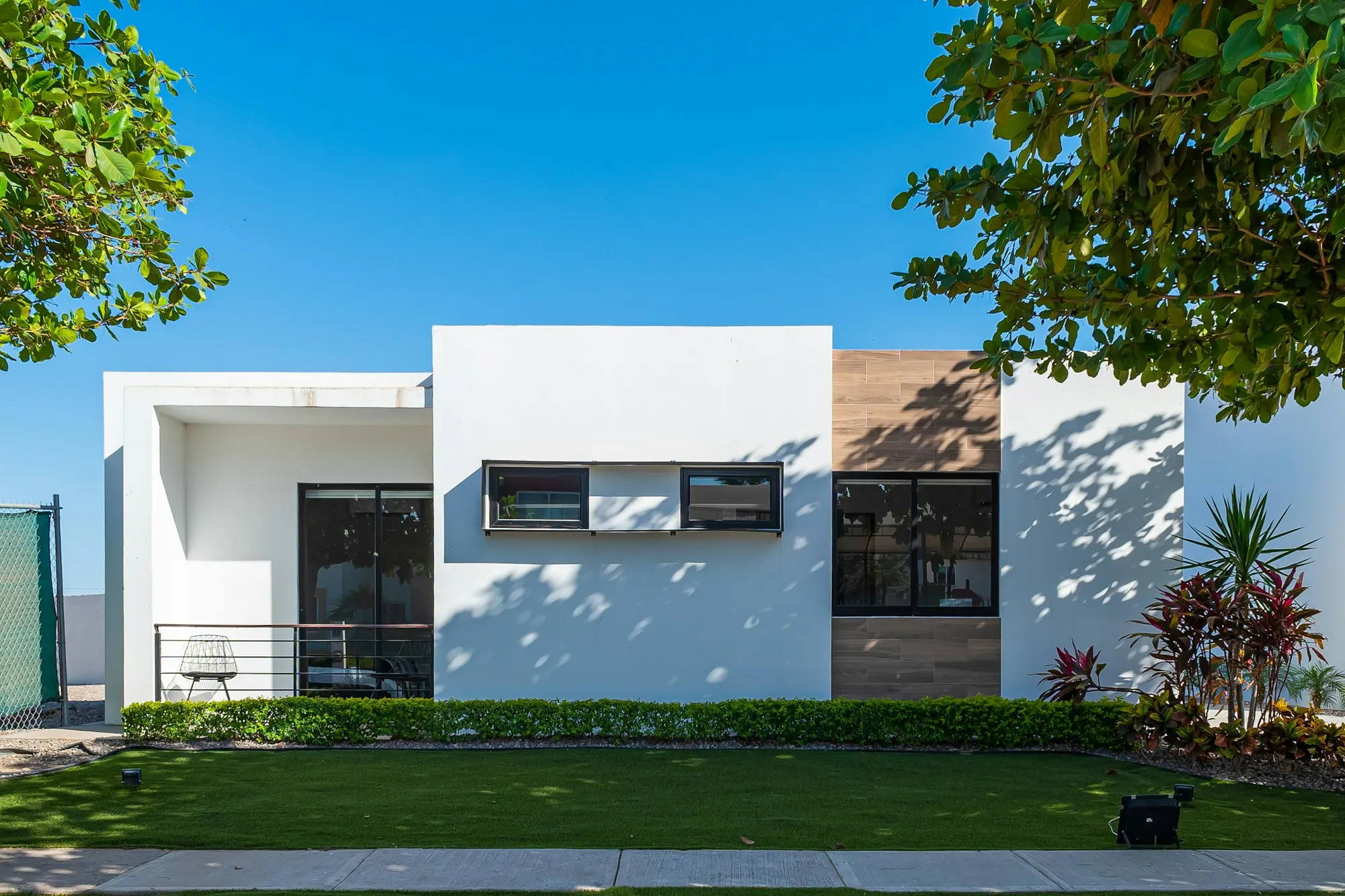 Modern white single-story house with flat roof and front lawn