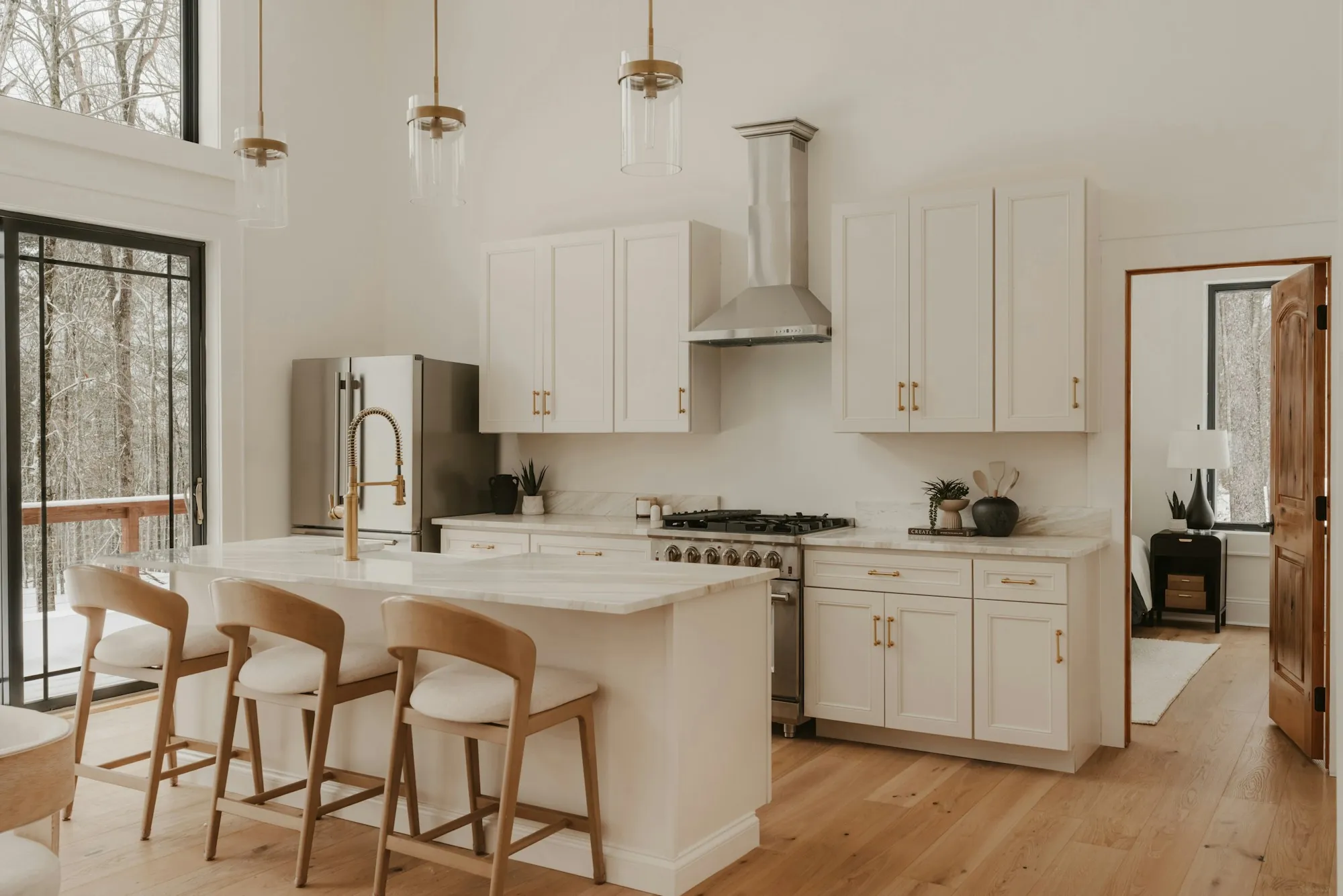 Kitchen with white cabinets, a range hood and wooden stools